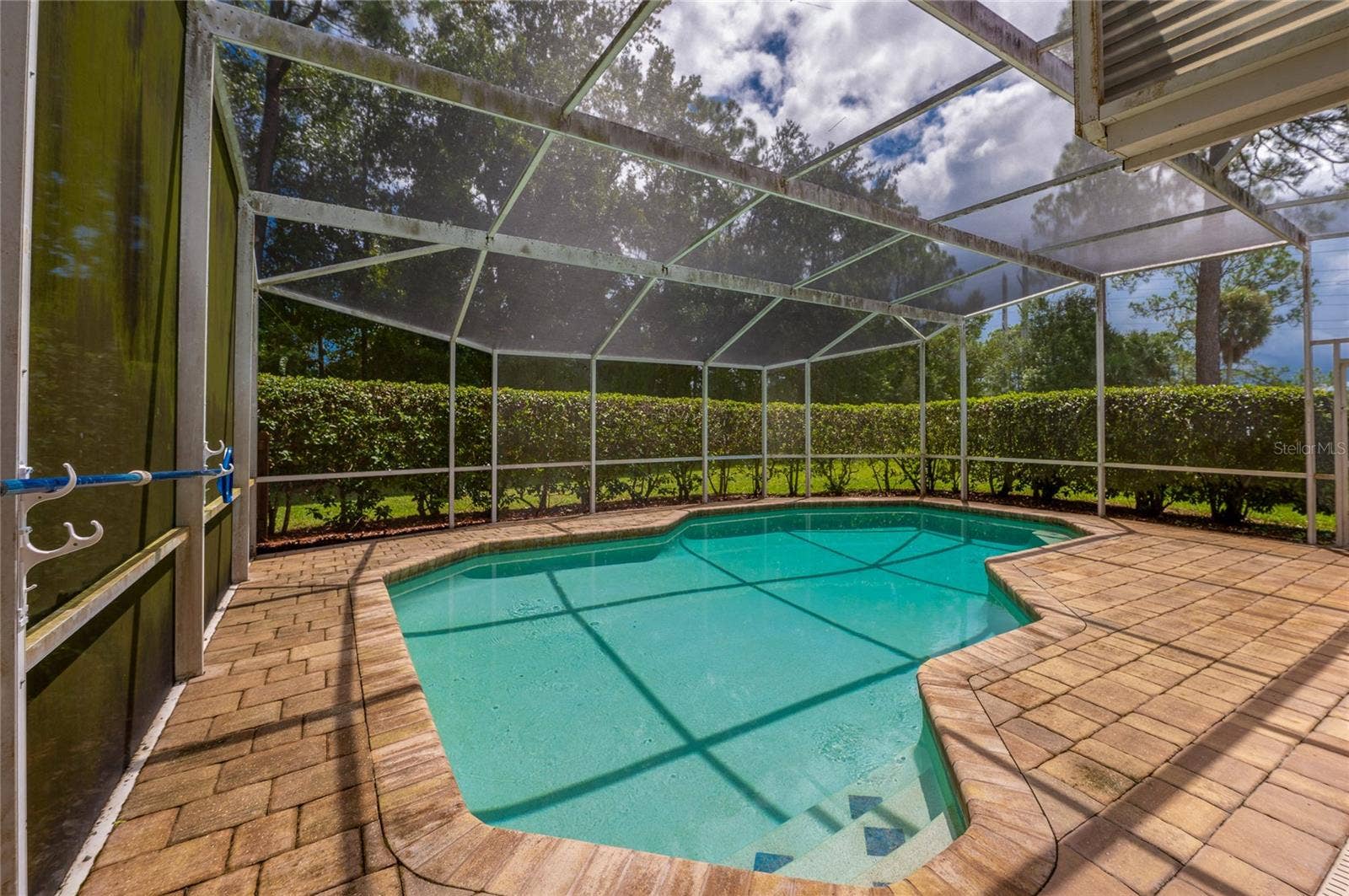 4669 SECRET RIVER TRAIL, Port Orange, FL 32129 Screened-in pool deck area featuring a paved surround and private hedge line along the perimeter.