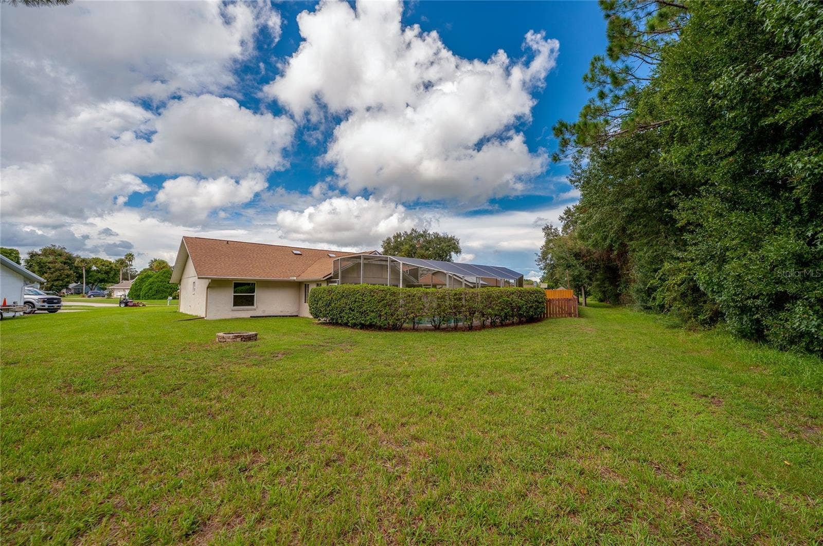 4669 SECRET RIVER TRAIL, Port Orange, FL 32129 Wide view of the open lawn framing the rear exterior of the home, complete with lush green grass and mature privacy landscaping.