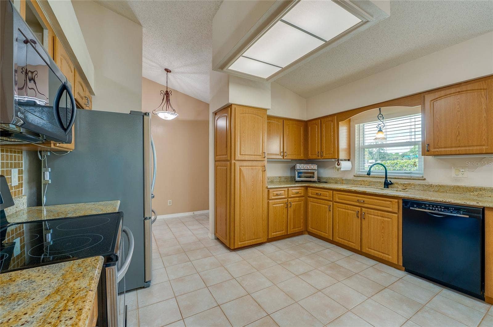 4669 SECRET RIVER TRAIL, Port Orange, FL 32129 Well-appointed kitchen featuring solid wood cabinets, granite countertops, black and stainless steel appliances, and tile flooring.