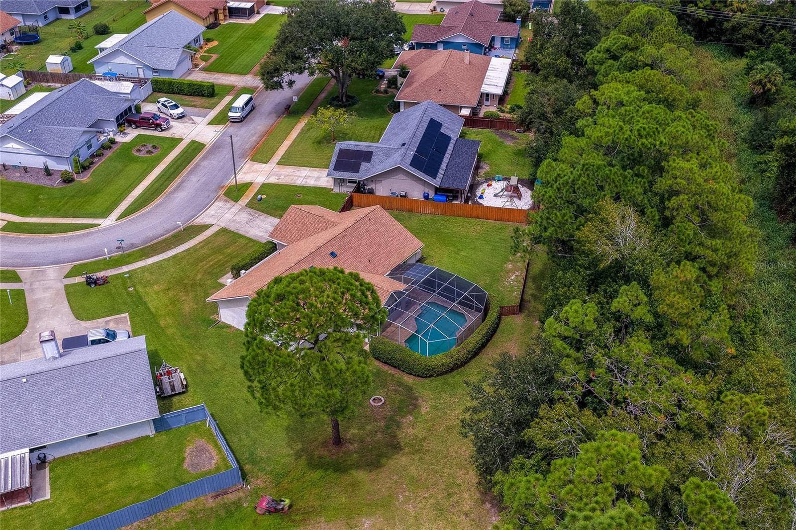 4669 SECRET RIVER TRAIL, Port Orange, FL 32129 Birds-eye view focusing on the backyard pool structure, large lawn, and dense tree-lined privacy buffer.