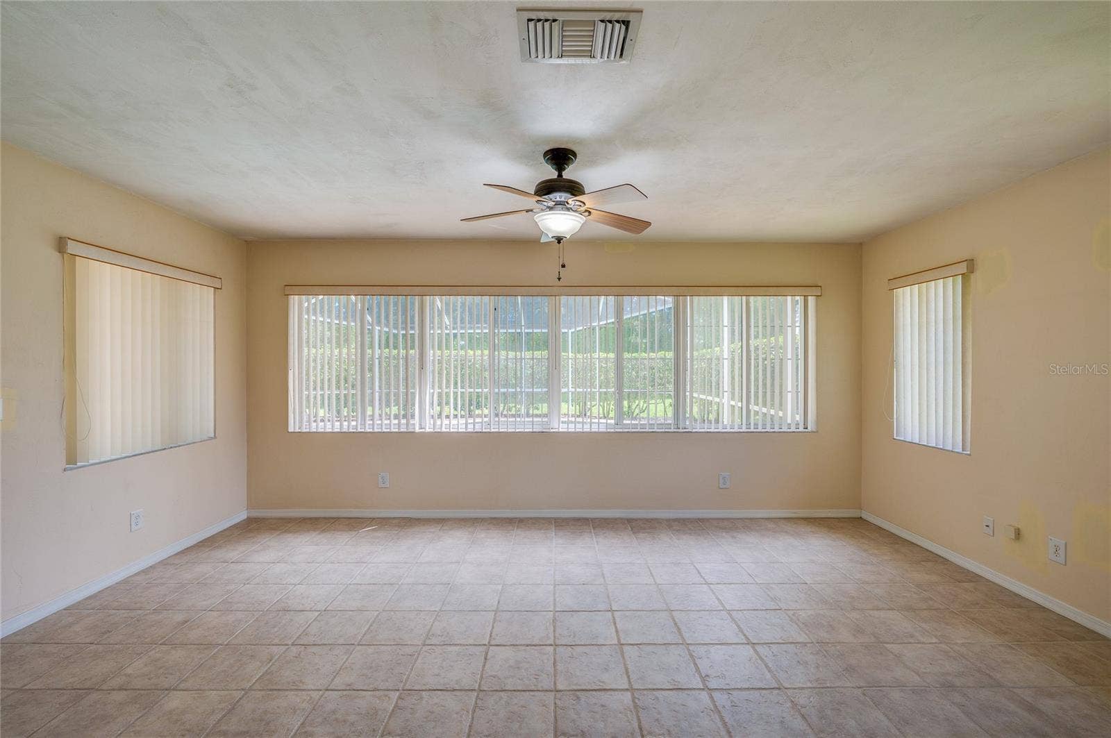 4669 SECRET RIVER TRAIL, Port Orange, FL 32129 Bright enclosed sunroom equipped with light beige tile flooring, a ceiling fan, and wide windows fitted with vertical blinds for controlled light.