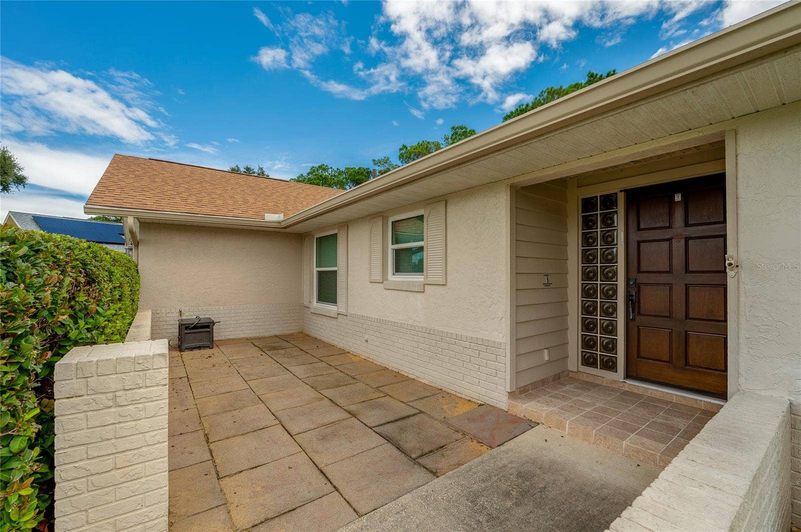 4669 SECRET RIVER TRAIL, Port Orange, FL 32129 Welcoming front entry patio framed by brick half-walls, tiled walkways, and decorative glass block accents by the door.