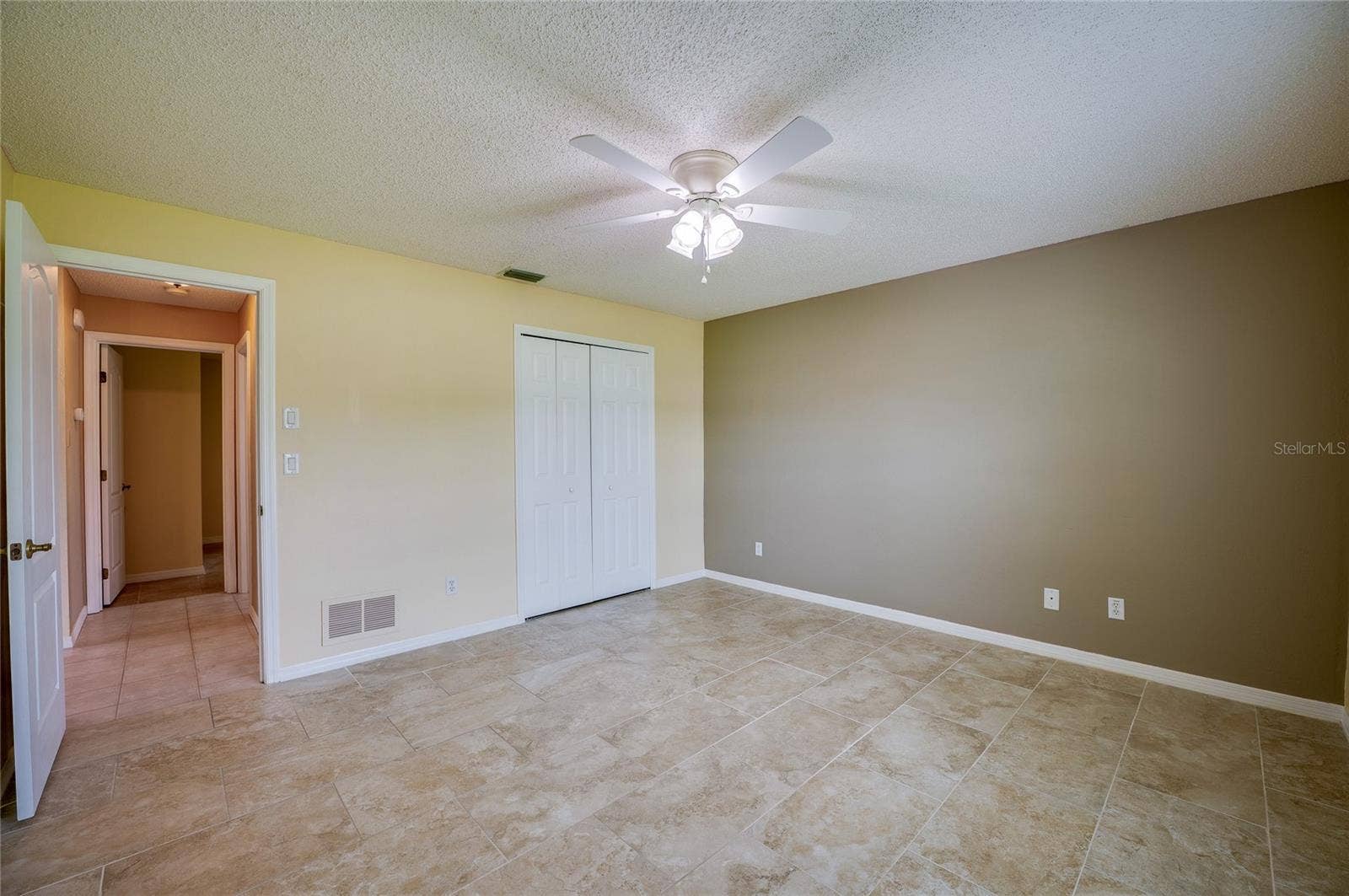 4669 SECRET RIVER TRAIL, Port Orange, FL 32129 Spacious room showcasing easy-to-clean tile flooring, double closet doors, and an open doorway leading to adjacent hall spaces.