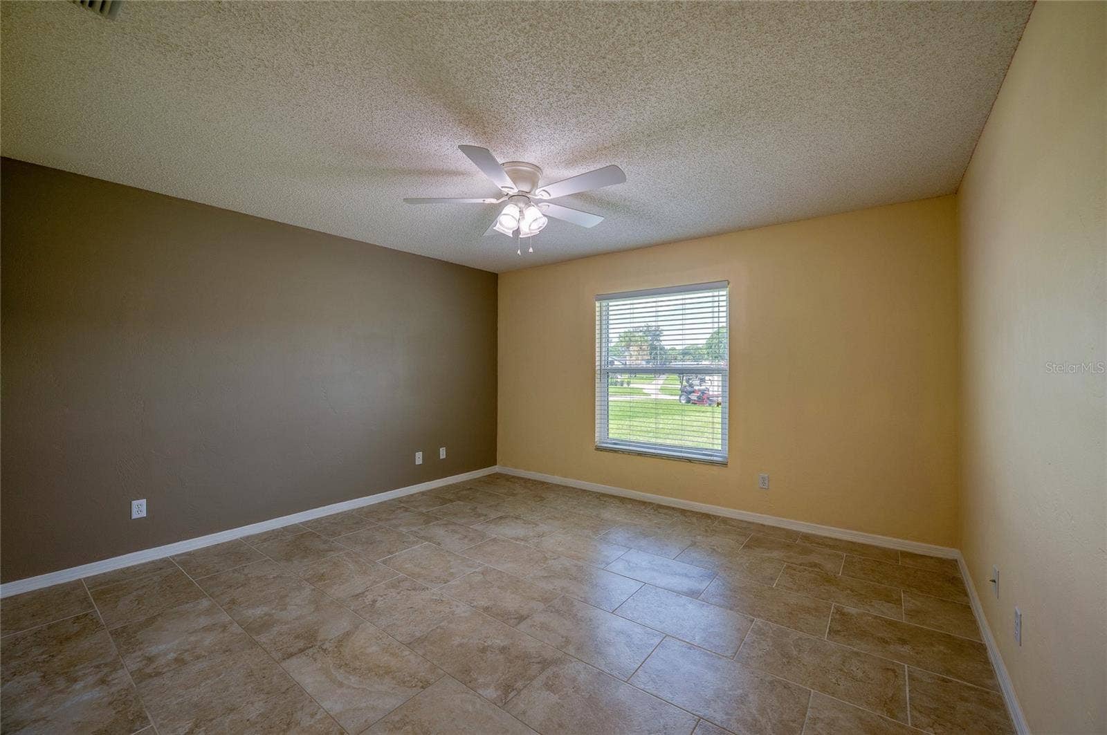 4669 SECRET RIVER TRAIL, Port Orange, FL 32129 Generous bedroom featuring neutral tiled flooring, dual-tone walls, and a central ceiling fan with integrated lighting. Large window with blinds allows for ample natural light.