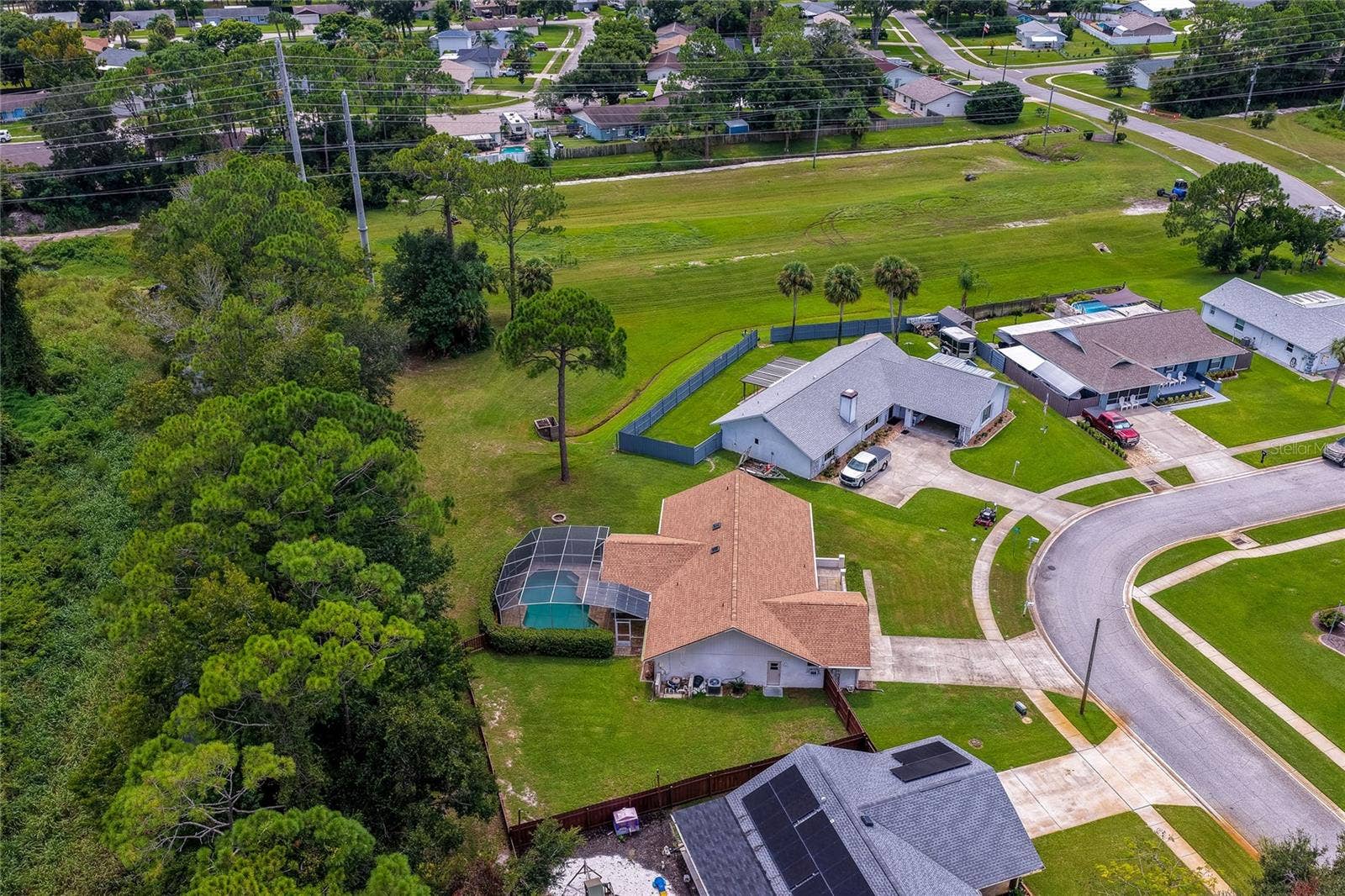 4669 SECRET RIVER TRAIL, Port Orange, FL 32129 Angled aerial photo capturing the home placement, screened lanai, and generous lot size.