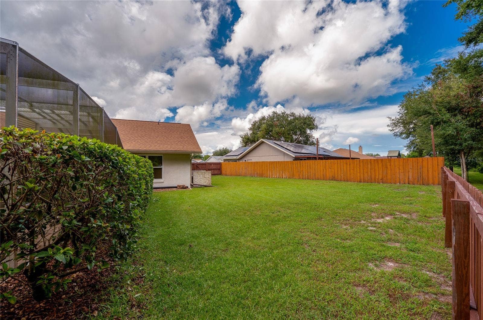 4669 SECRET RIVER TRAIL, Port Orange, FL 32129 Fenced side yard with a generous stretch of green lawn and mature hedging along the pool structure.