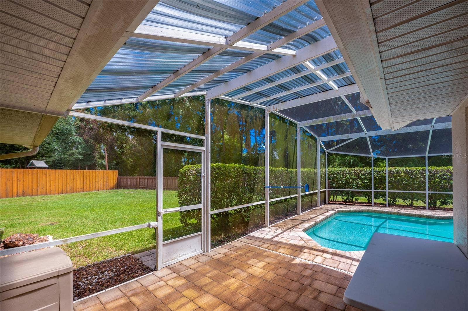 4669 SECRET RIVER TRAIL, Port Orange, FL 32129 Paved patio area leading to a screened-in swimming pool enclosure with views of the grassy lawn.