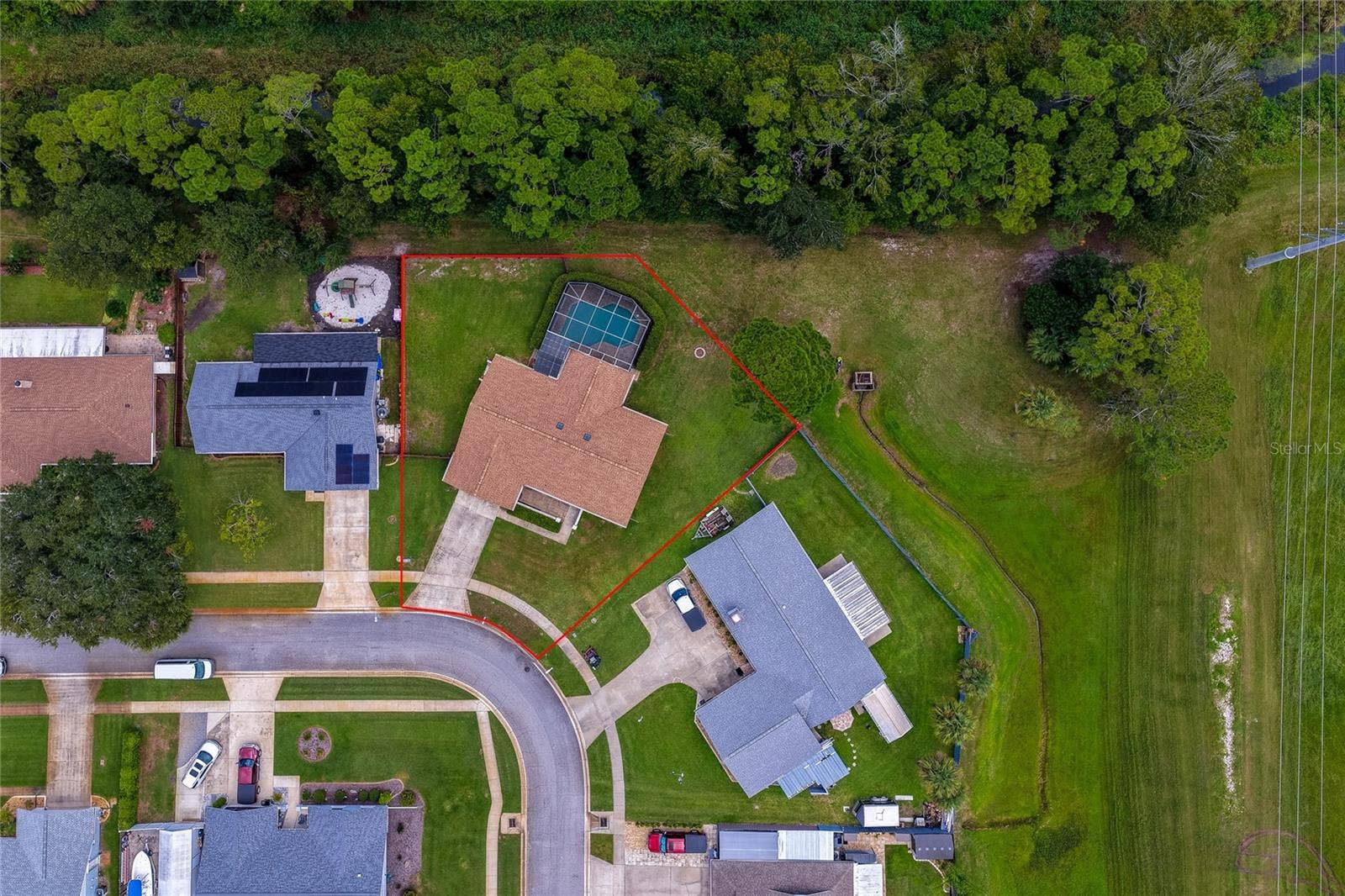 4669 SECRET RIVER TRAIL, Port Orange, FL 32129 Overhead aerial shot outlining the expansive property boundary, screened pool enclosure, and surrounding green spaces.