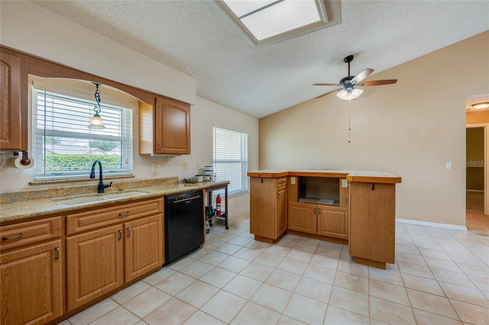 4669 SECRET RIVER TRAIL, Port Orange, FL 32129 Bright kitchen featuring warm wood cabinetry, neutral countertops, a ceiling fan, and durable tile flooring throughout.