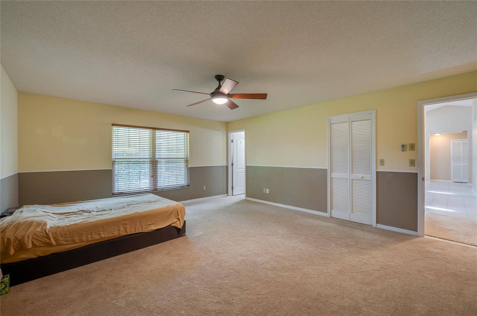 4669 SECRET RIVER TRAIL, Port Orange, FL 32129 Generously sized bedroom offering wall-to-wall carpeting, two-tone neutral walls, a ceiling fan light fixture, and louvered closet doors.