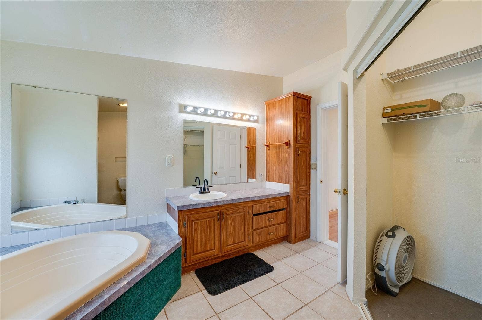 13 LAWRENCE COURT, Port Orange, FL 32127 Additional view of the primary bath highlights the corner soaking tub, extended vanity, generous cabinetry, large mirrors, and adjacent closet storage.