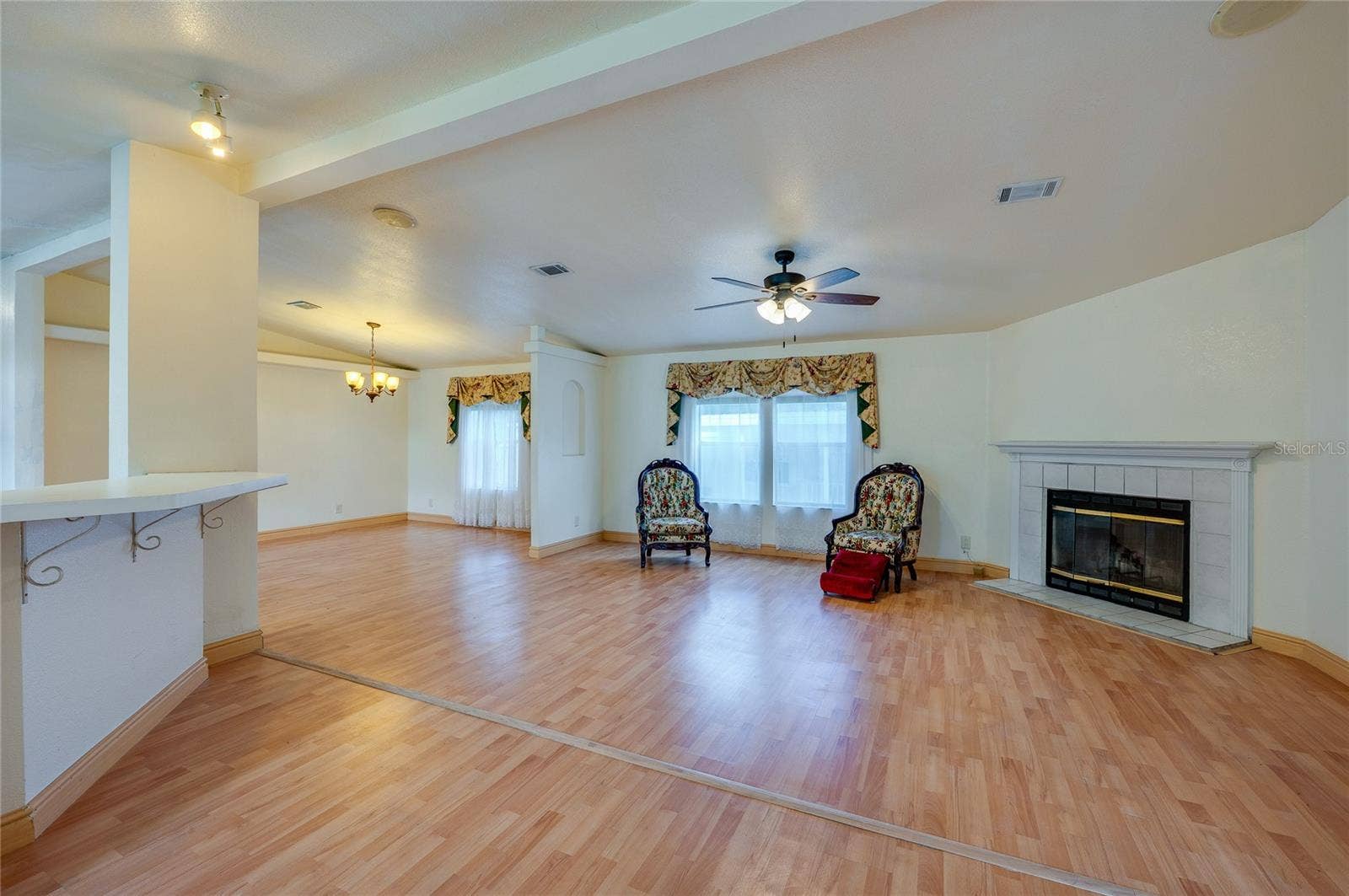 13 LAWRENCE COURT, Port Orange, FL 32127 Another view highlights the generous living space, large windows, fireplace, and open sightlines into the dining area.