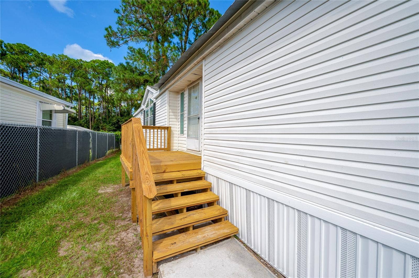 13 LAWRENCE COURT, Port Orange, FL 32127 Wood steps and a raised landing provide access to the home, with a grassy side yard alongside the residence.