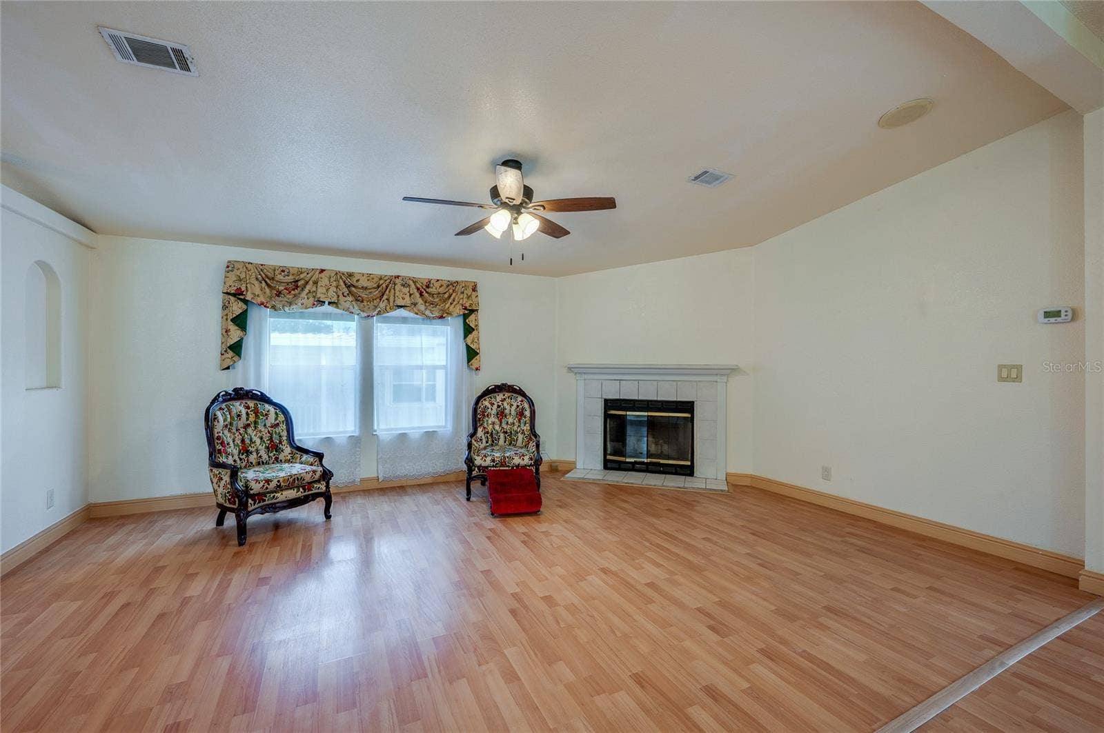 13 LAWRENCE COURT, Port Orange, FL 32127 Bright living room offers plenty of flexibility for seating and entertaining, with a fireplace, ceiling fan, and large front-facing windows.