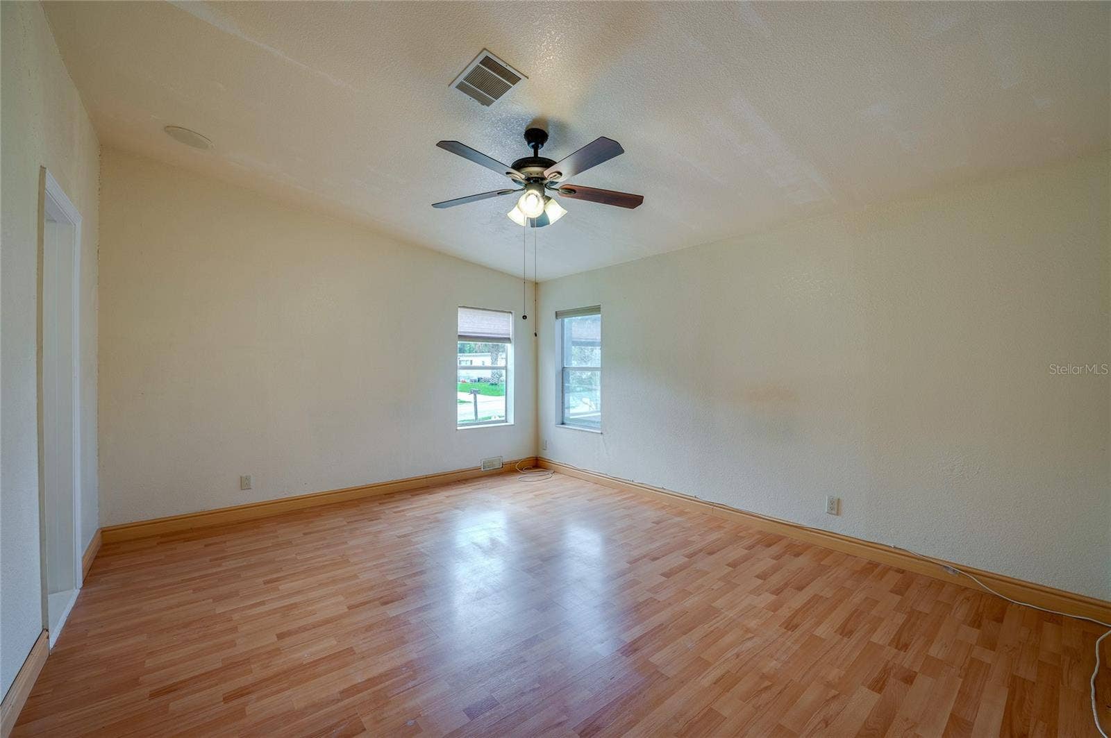 13 LAWRENCE COURT, Port Orange, FL 32127 Generously sized primary bedroom with a ceiling fan, multiple windows for natural light, and ample wall space for a variety of furniture arrangements.