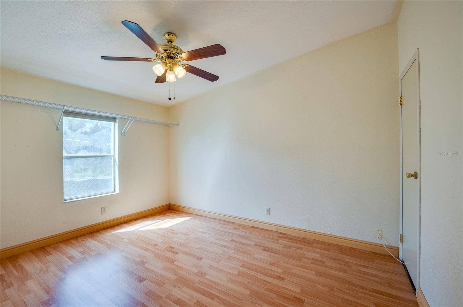 13 LAWRENCE COURT, Port Orange, FL 32127 Bright bedroom features a ceiling fan, window for natural light, and ample open space for flexible furniture placement.