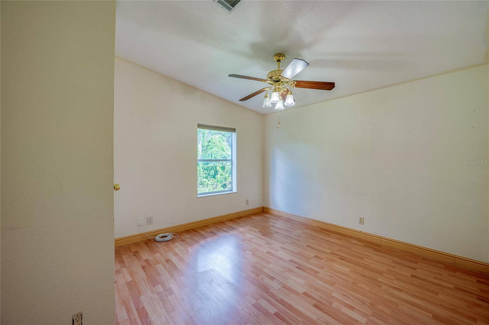 13 LAWRENCE COURT, Port Orange, FL 32127 Spacious bedroom offers a ceiling fan, natural light from a large window, and ample wall space for flexible furniture placement.