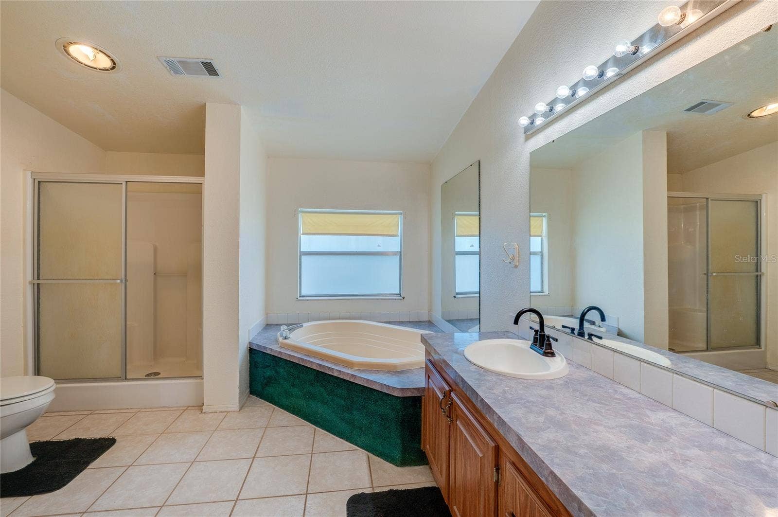 13 LAWRENCE COURT, Port Orange, FL 32127 Large bathroom includes a corner soaking tub, separate enclosed shower, extended vanity with oversized mirror, and tile flooring.