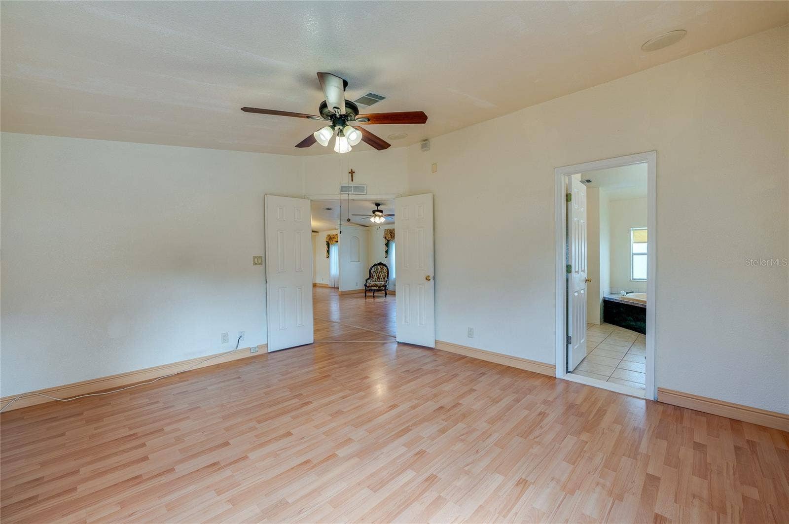 13 LAWRENCE COURT, Port Orange, FL 32127 Spacious primary bedroom features a ceiling fan, double-door entry, and convenient direct access to the adjoining bathroom.
