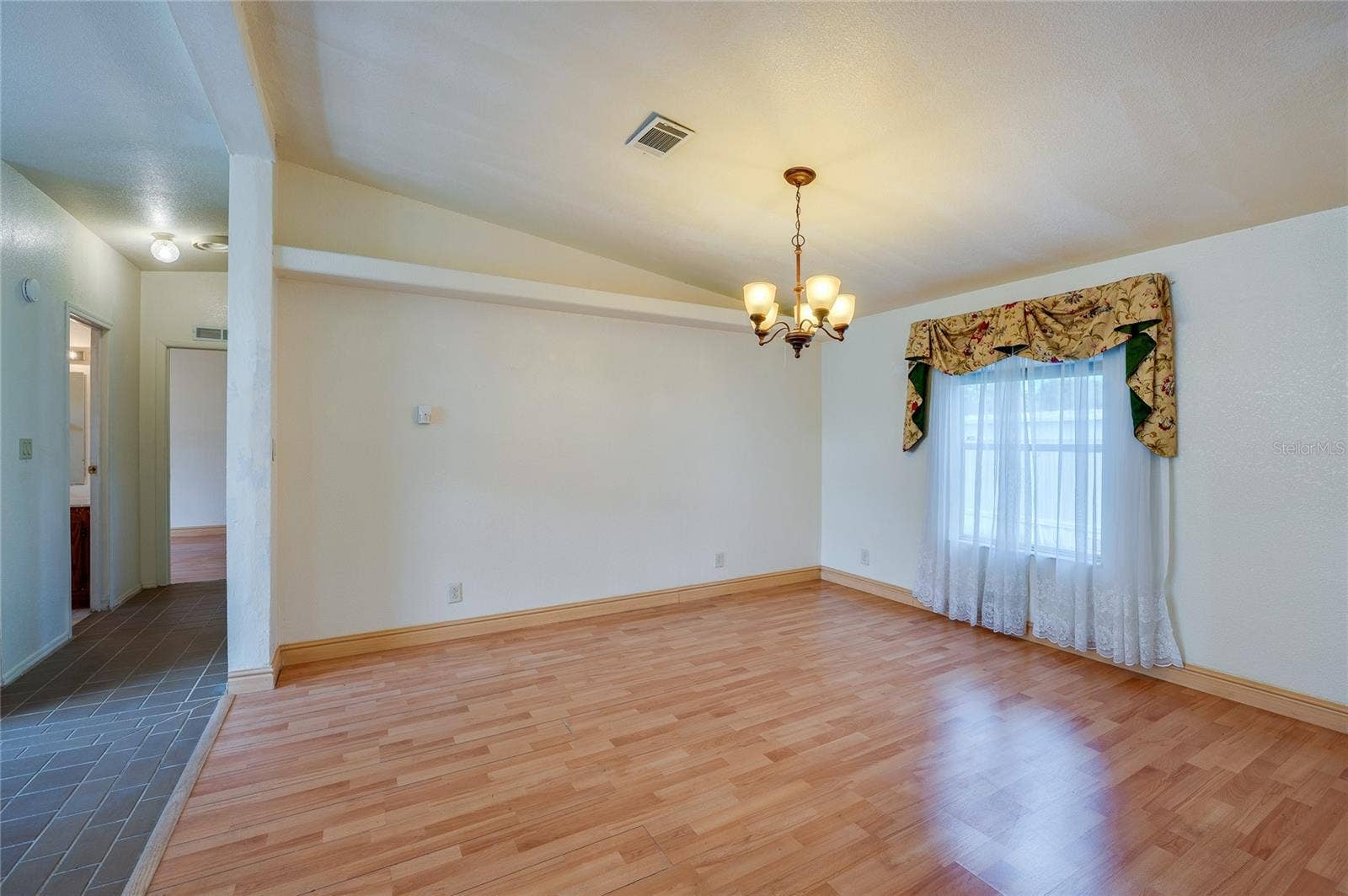13 LAWRENCE COURT, Port Orange, FL 32127 Defined dining space features a chandelier and a large window for natural light, with an open connection to the surrounding living areas.