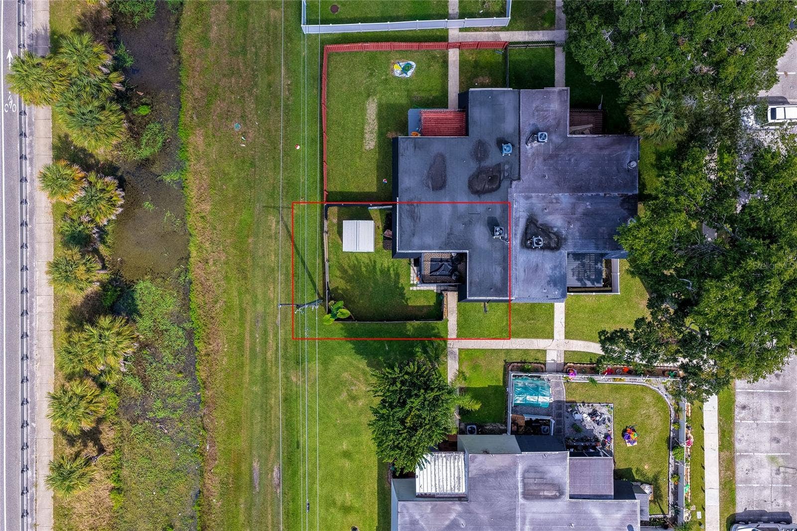 36 SPRINGWOOD SQUARE, Port Orange, FL 32129 Direct overhead aerial highlighting the property boundaries, unit footprint, and adjacent green buffer zone outlined in red.