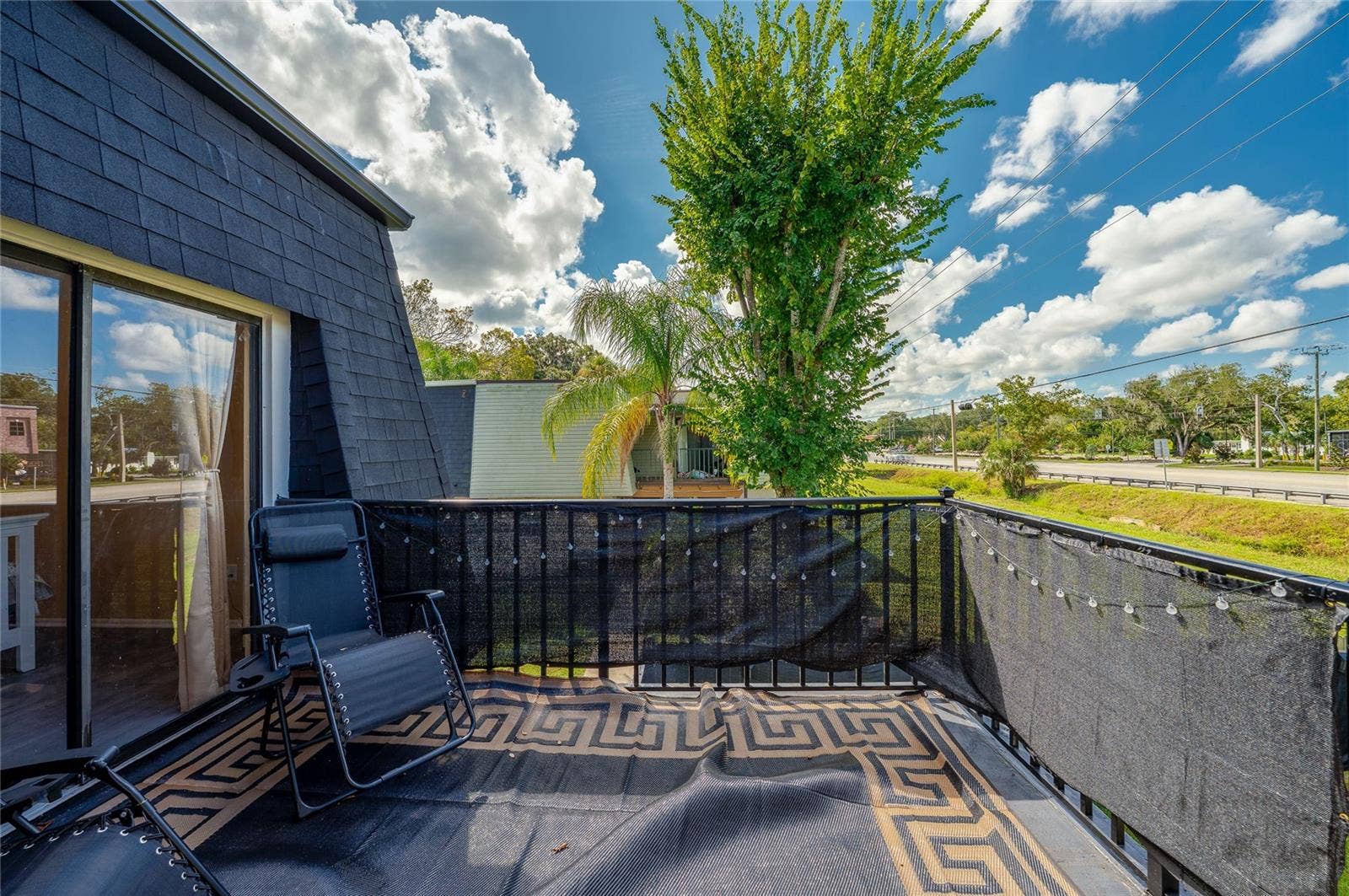 36 SPRINGWOOD SQUARE, Port Orange, FL 32129 Private upper-level balcony featuring black mesh privacy screening, a patterned floor mat, and open views of surrounding green space.