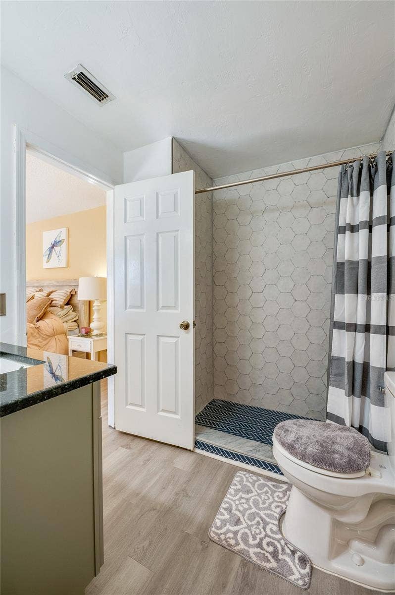 36 SPRINGWOOD SQUARE, Port Orange, FL 32129 Bathroom interior showcasing a tiled shower enclosure with herringbone floor tile and LVP flooring.