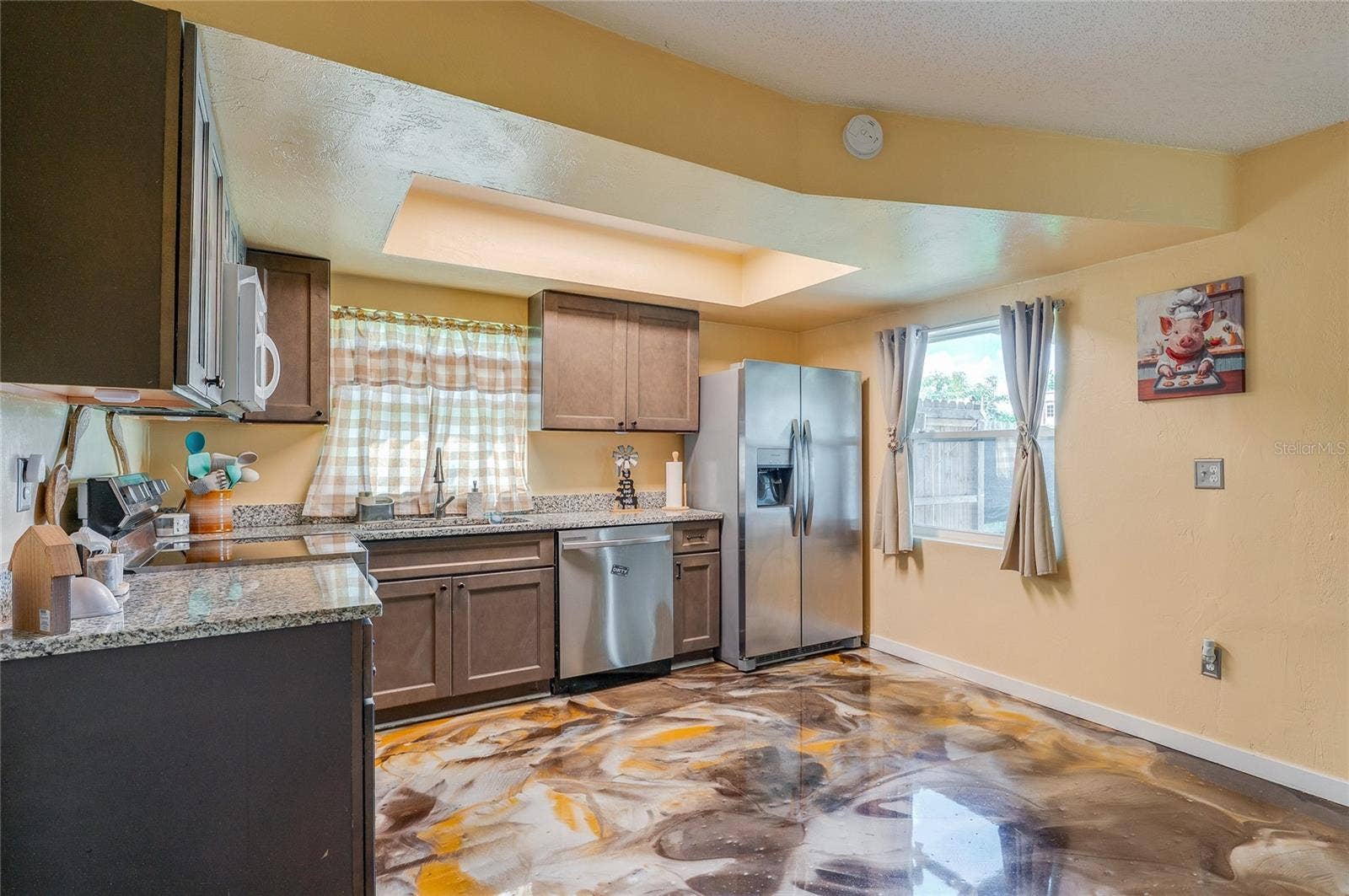 36 SPRINGWOOD SQUARE, Port Orange, FL 32129 Functional kitchen space featuring stainless steel appliances, dark cabinetry, granite countertops, and eye-catching epoxy flooring.