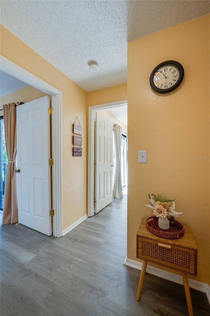 36 SPRINGWOOD SQUARE, Port Orange, FL 32129 Bright, welcoming hallway featuring light wood-look flooring, warm yellow walls, and smooth transitions to adjacent rooms.