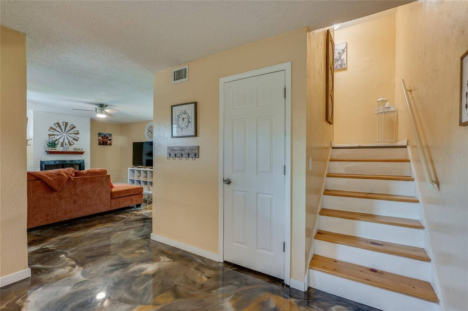 36 SPRINGWOOD SQUARE, Port Orange, FL 32129 Foyer and entryway showing wooden stair steps with white risers, epoxy flooring, and access to an adjacent living area.