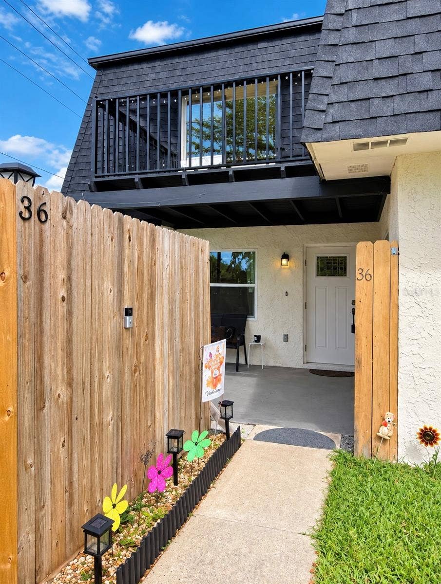 36 SPRINGWOOD SQUARE, Port Orange, FL 32129 Exterior entry pathway guided by a wooden privacy fence.
