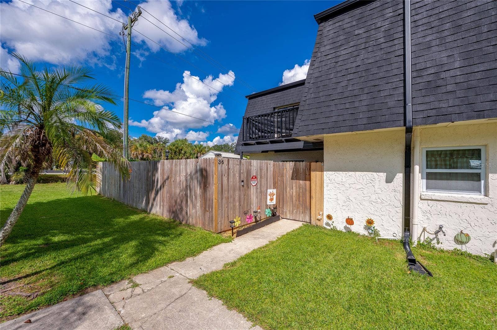 36 SPRINGWOOD SQUARE, Port Orange, FL 32129 Exterior entry pathway guided by a wooden privacy fence.