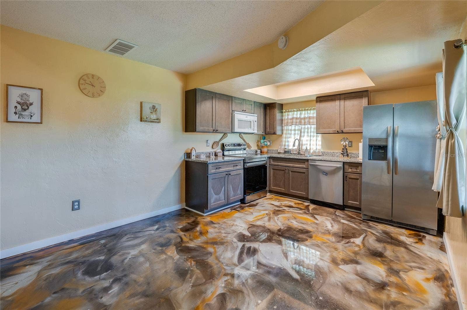 36 SPRINGWOOD SQUARE, Port Orange, FL 32129 Functional kitchen equipped with stainless steel appliances, dark wooden cabinetry, granite countertops, and epoxy flooring.