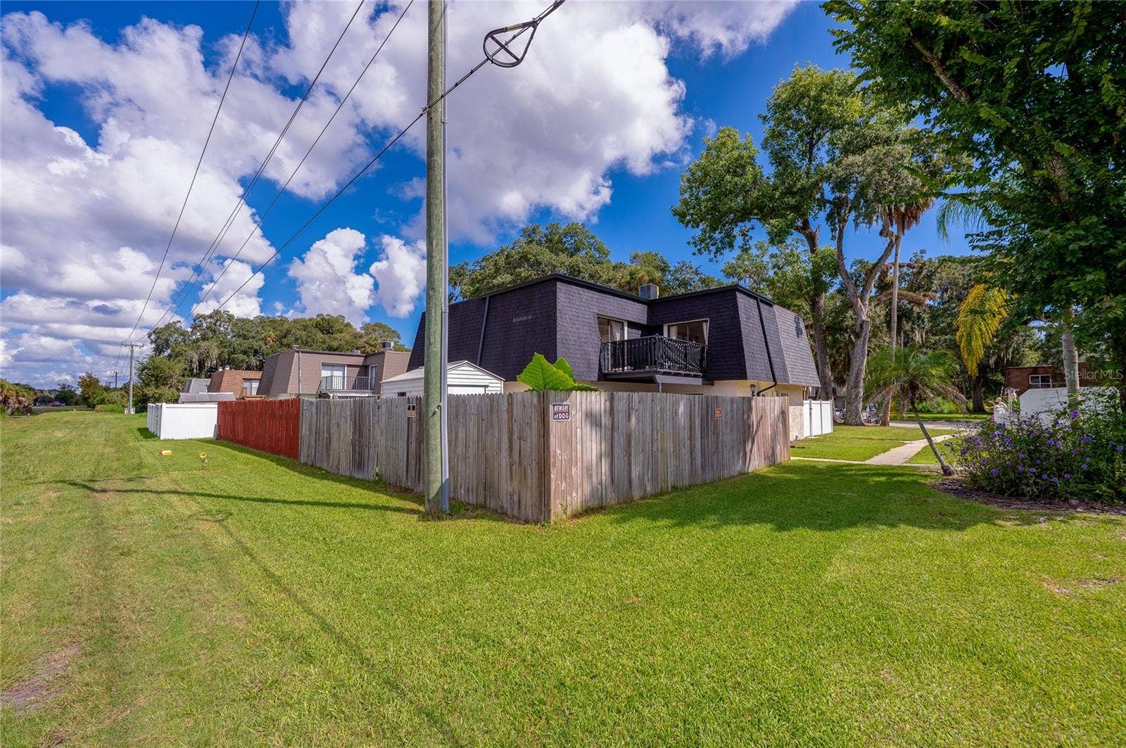 36 SPRINGWOOD SQUARE, Port Orange, FL 32129 Corner perspective highlighting the fully enclosed yard, roofline, and surrounding green lawn space.