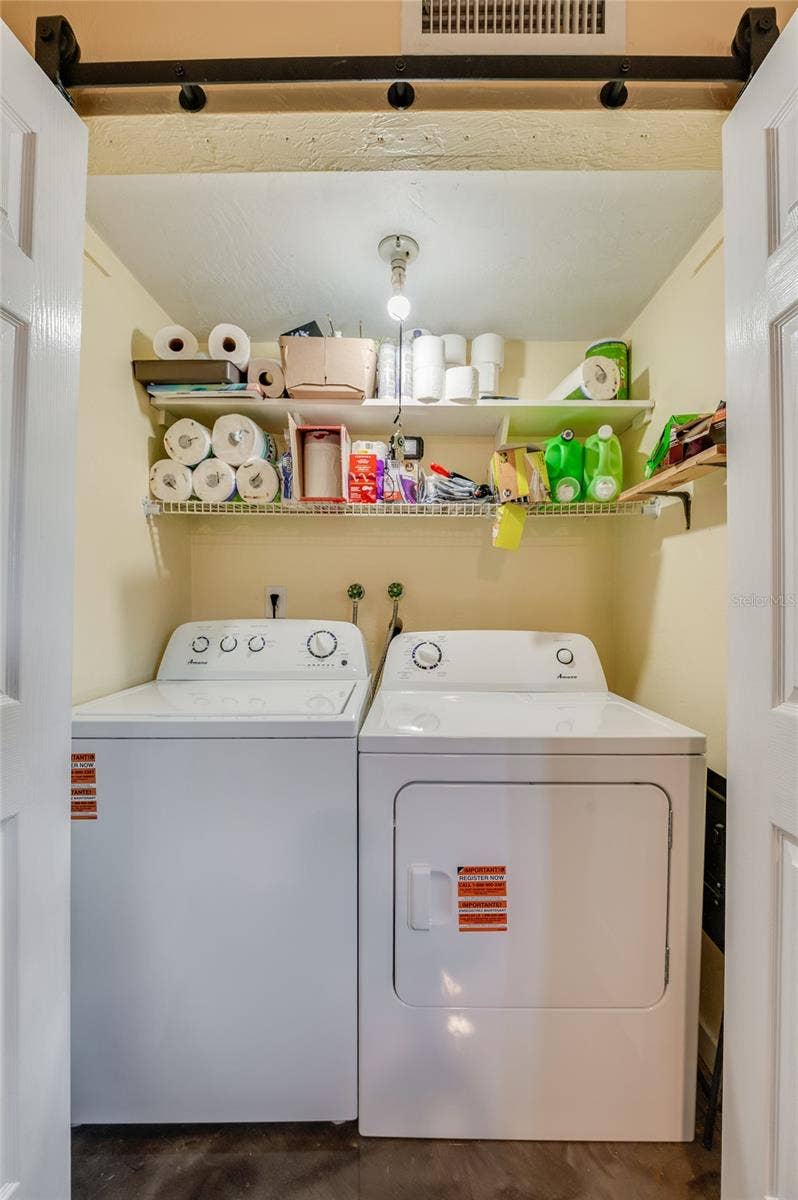 36 SPRINGWOOD SQUARE, Port Orange, FL 32129 Convenient laundry nook complete with side-by-side washer and dryer units and overhead wire shelving for extra storage.