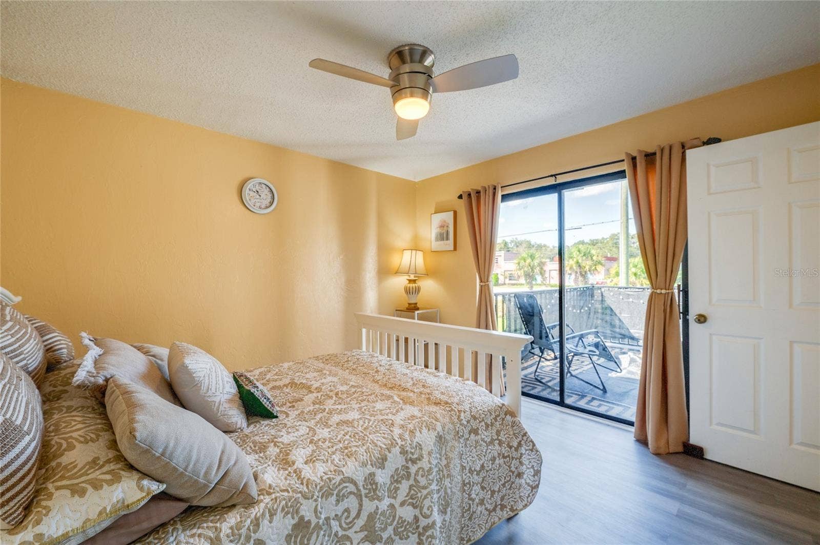 36 SPRINGWOOD SQUARE, Port Orange, FL 32129 Bright room with LVP flooring, a modern ceiling fan, and sliding glass door access to a private balcony.