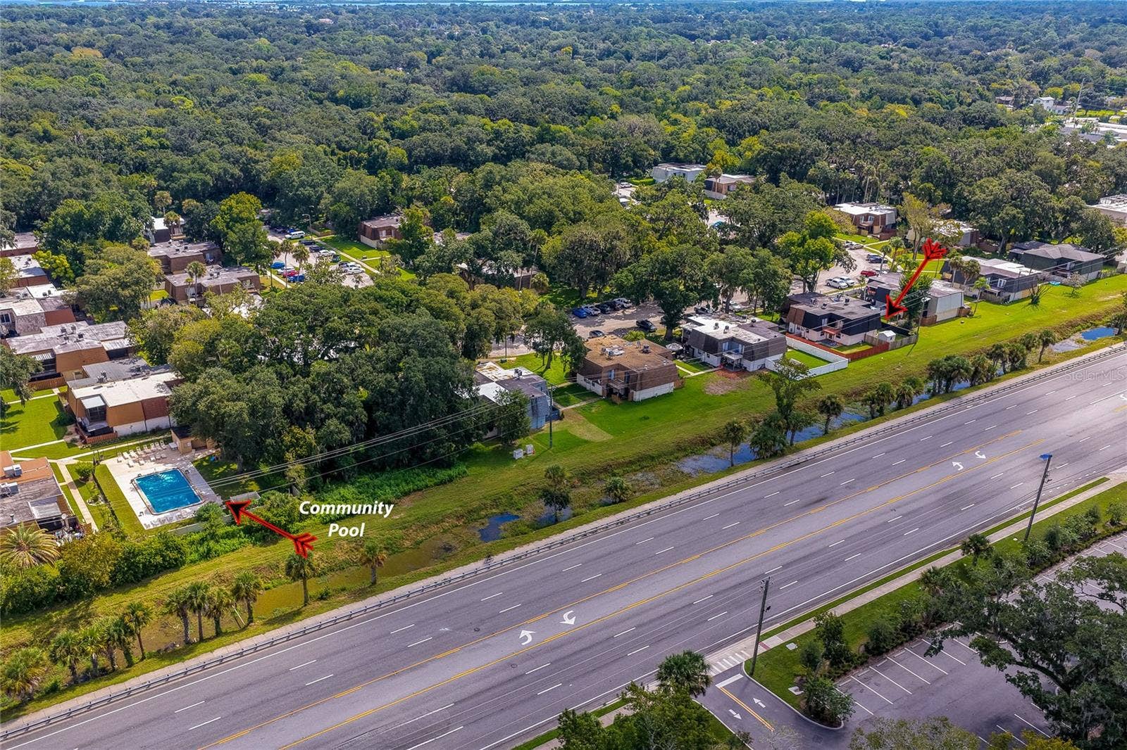 36 SPRINGWOOD SQUARE, Port Orange, FL 32129 Wide aerial view showcasing the community's layout, highlighting its green surroundings, proximity to the main roadway, and the nearby community pool area.