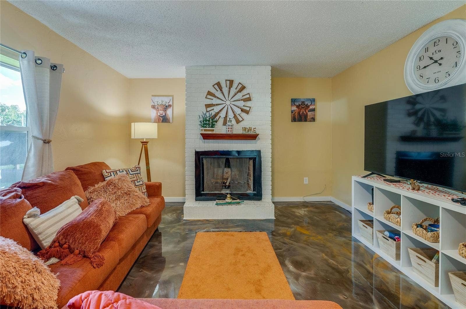 36 SPRINGWOOD SQUARE, Port Orange, FL 32129 Cozy living room space centered around a painted white brick fireplace and hearth with large windows allowing for ample natural light.
