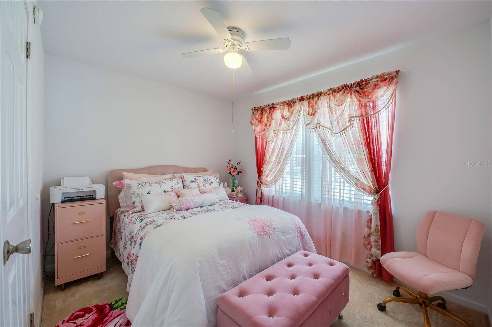 60 GOLDEN GATE CIRCLE, Port Orange, FL 32129 Charming bedroom space showcasing neutral wall finishes, soft carpeted flooring, and a integrated white ceiling fan. Windows fill the room with natural light.
