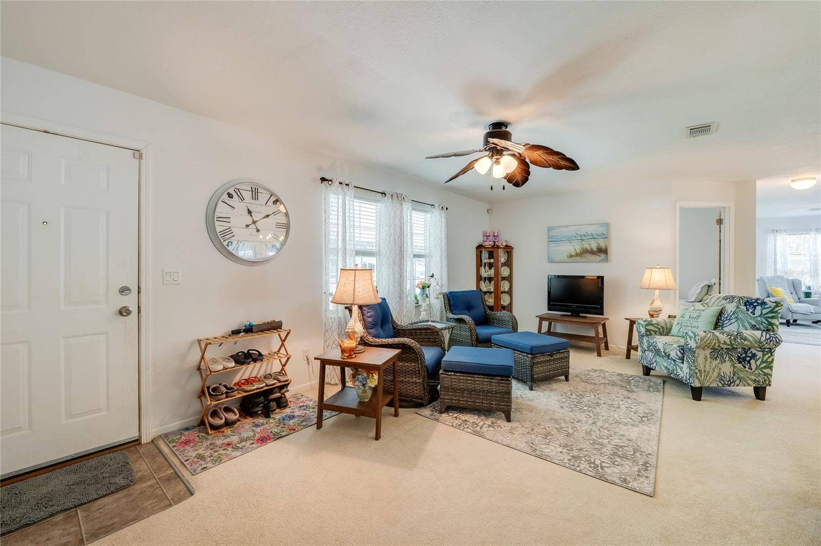60 GOLDEN GATE CIRCLE, Port Orange, FL 32129 Welcoming entryway and living space highlighting high ceilings, natural light through double-hung windows, and light neutral flooring. An open doorway provides smooth traffic flow into the adjoining rooms.