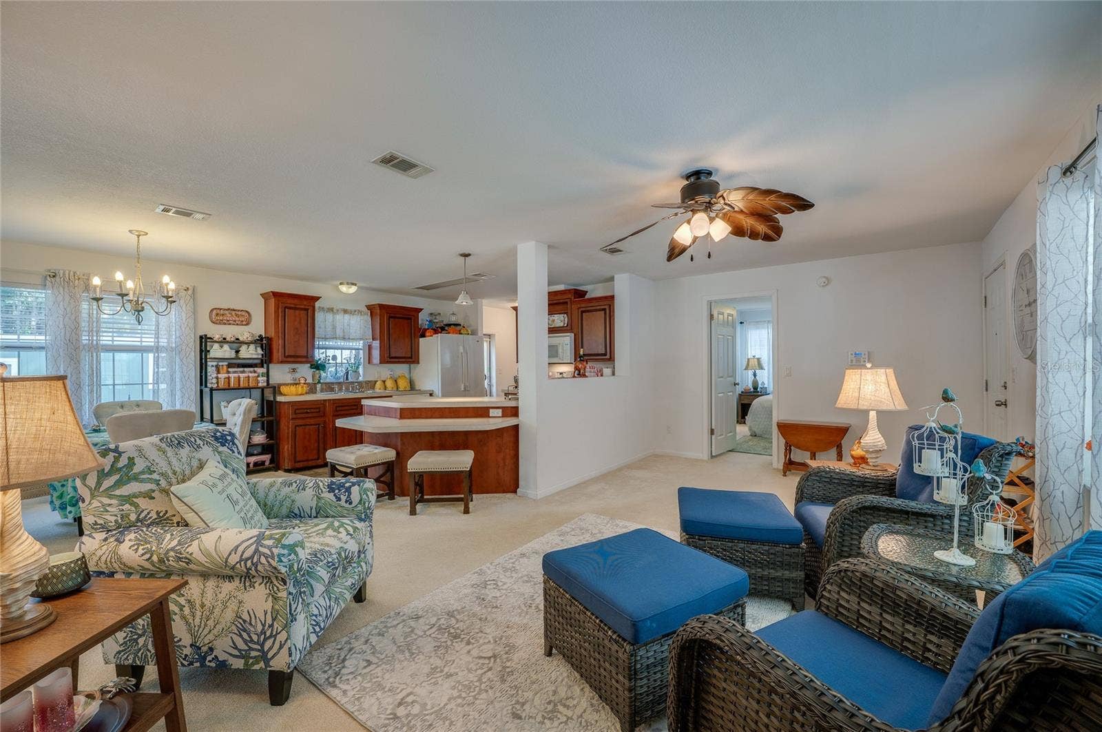 60 GOLDEN GATE CIRCLE, Port Orange, FL 32129 Expansive view of the open floor plan showcasing the continuous flow between the living room, kitchen, and dining spaces. Large windows and neutral finishes create a light, cohesive atmosphere throughout.