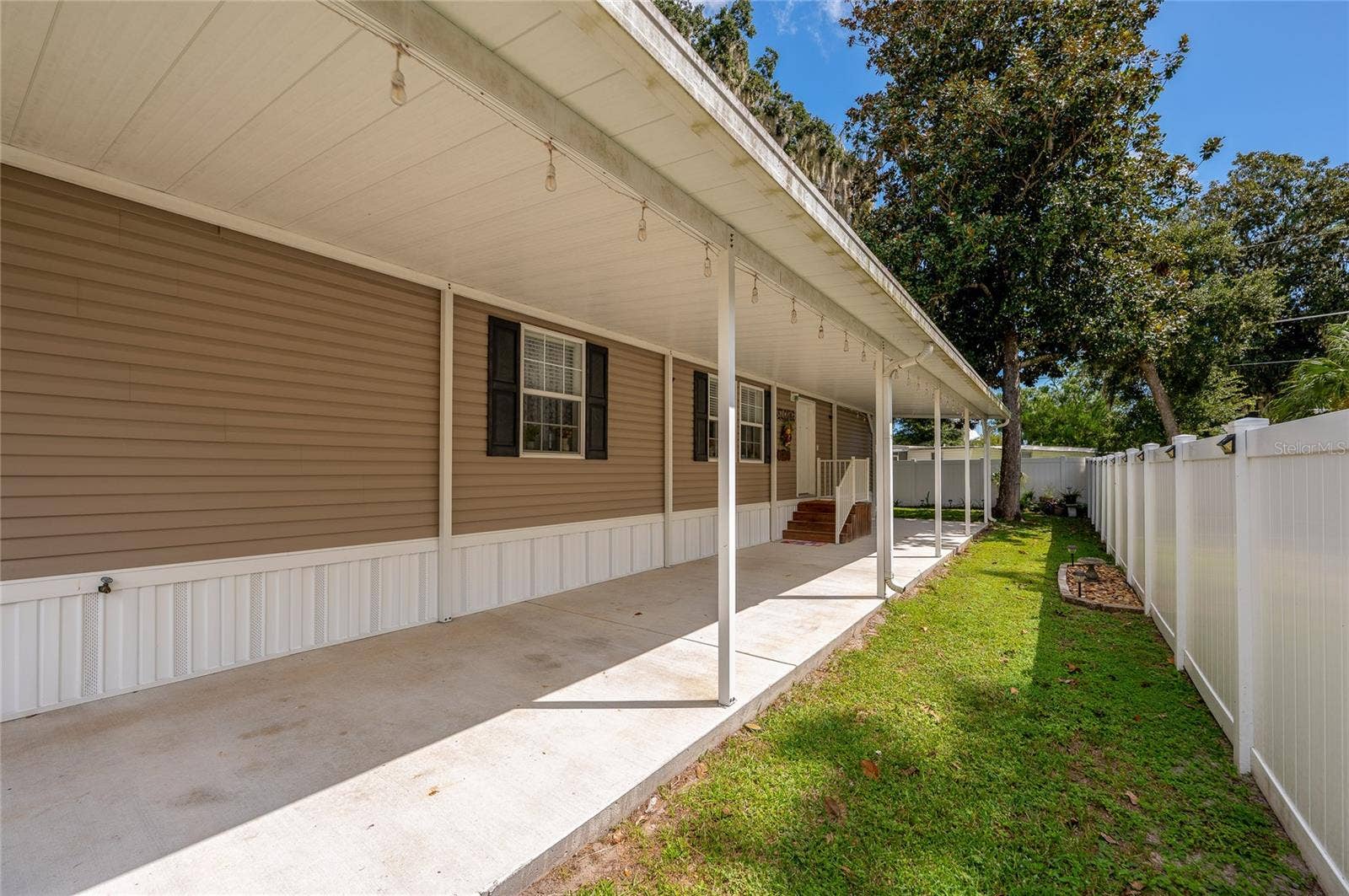 60 GOLDEN GATE CIRCLE, Port Orange, FL 32129 Long, covered concrete driveway providing ample sheltered parking alongside the home's exterior.