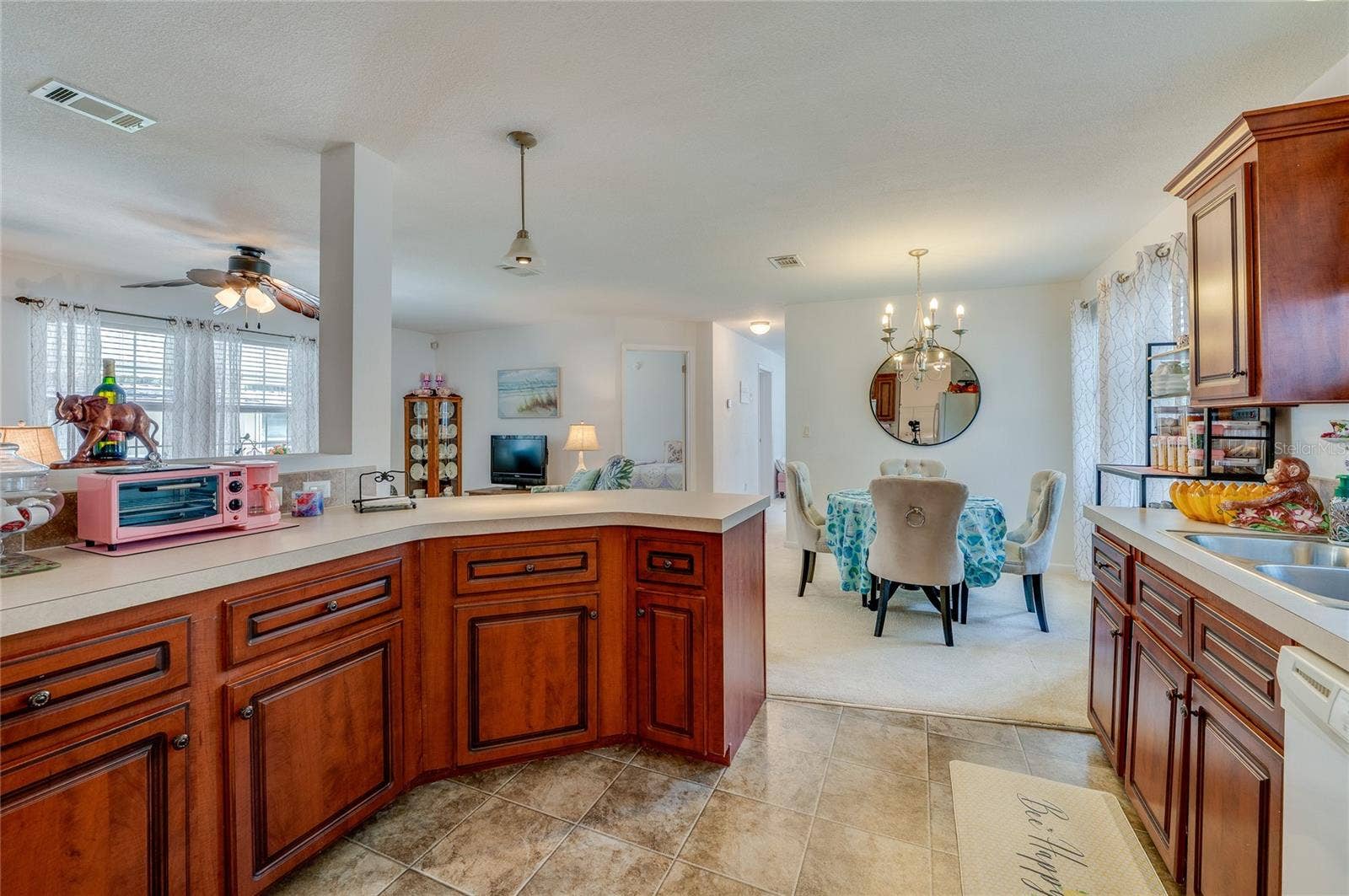 60 GOLDEN GATE CIRCLE, Port Orange, FL 32129 Spacious kitchen workspace featuring continuous countertop surfaces, rich wood cabinets, and smooth linoleum flooring. The open design flows effortlessly into the nearby dining area.