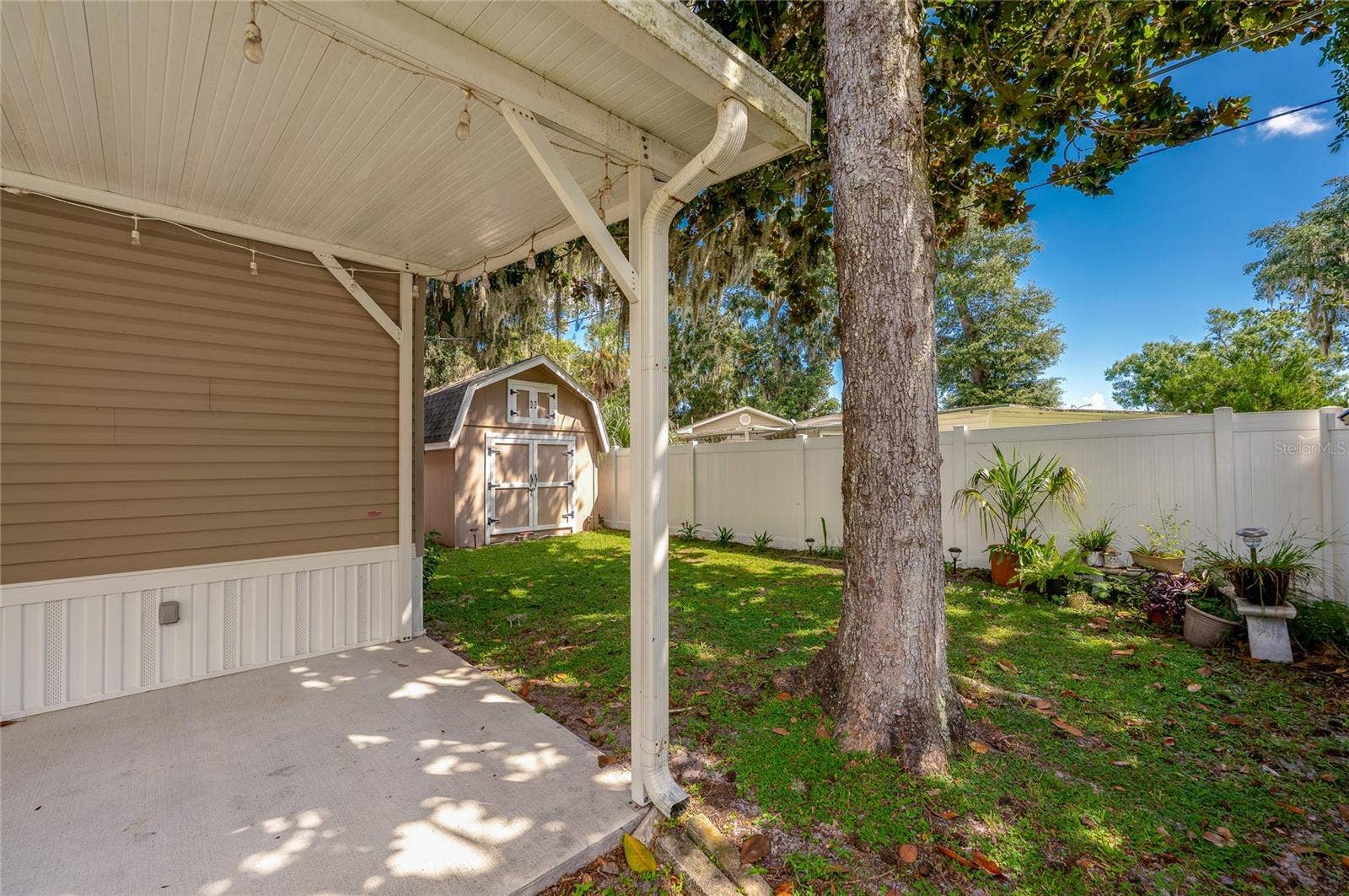 60 GOLDEN GATE CIRCLE, Port Orange, FL 32129 Covered concrete patio space overlooking the lush lawn and white privacy fencing.