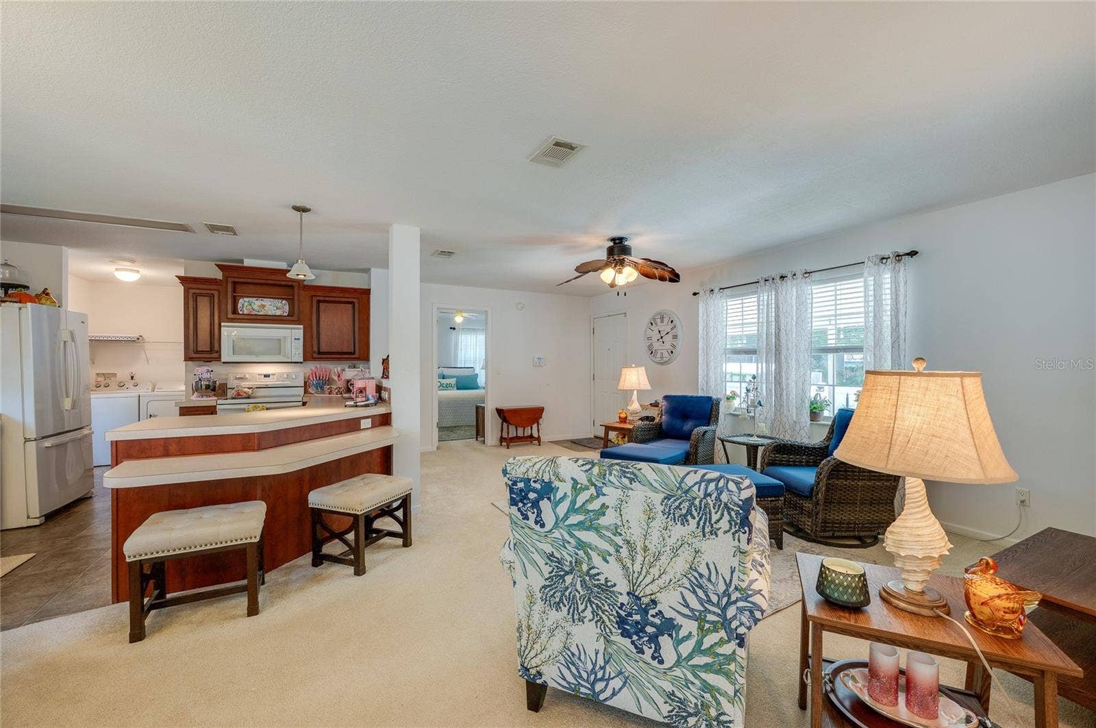 60 GOLDEN GATE CIRCLE, Port Orange, FL 32129 Open-concept interior featuring a raised breakfast bar that bridges the kitchen and main living space. Large windows and a ceiling fan keep the expansive layout feeling airy and bright.