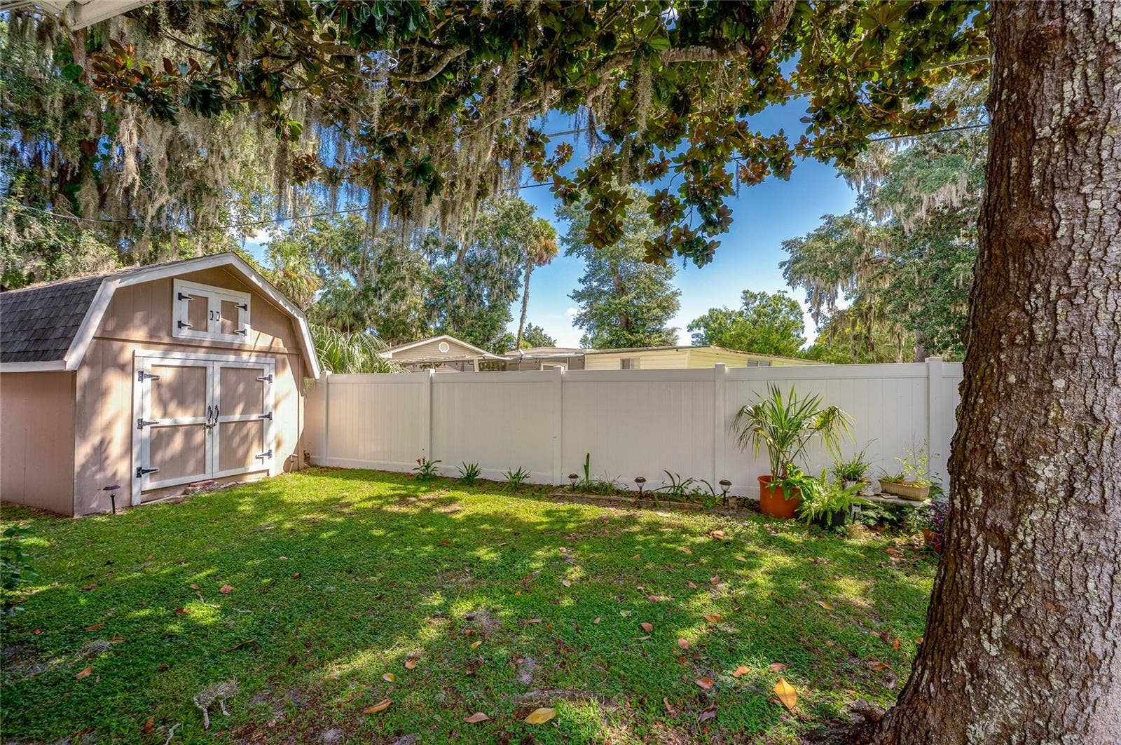 60 GOLDEN GATE CIRCLE, Port Orange, FL 32129 Fenced backyard area featuring a detached storage shed, green lawn, and mature trees.