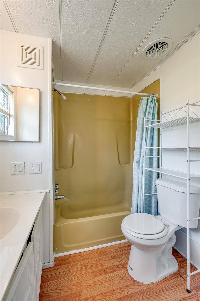 Full bathroom with a tub/shower combination, vanity, window for natural light, and additional over-toilet storage.