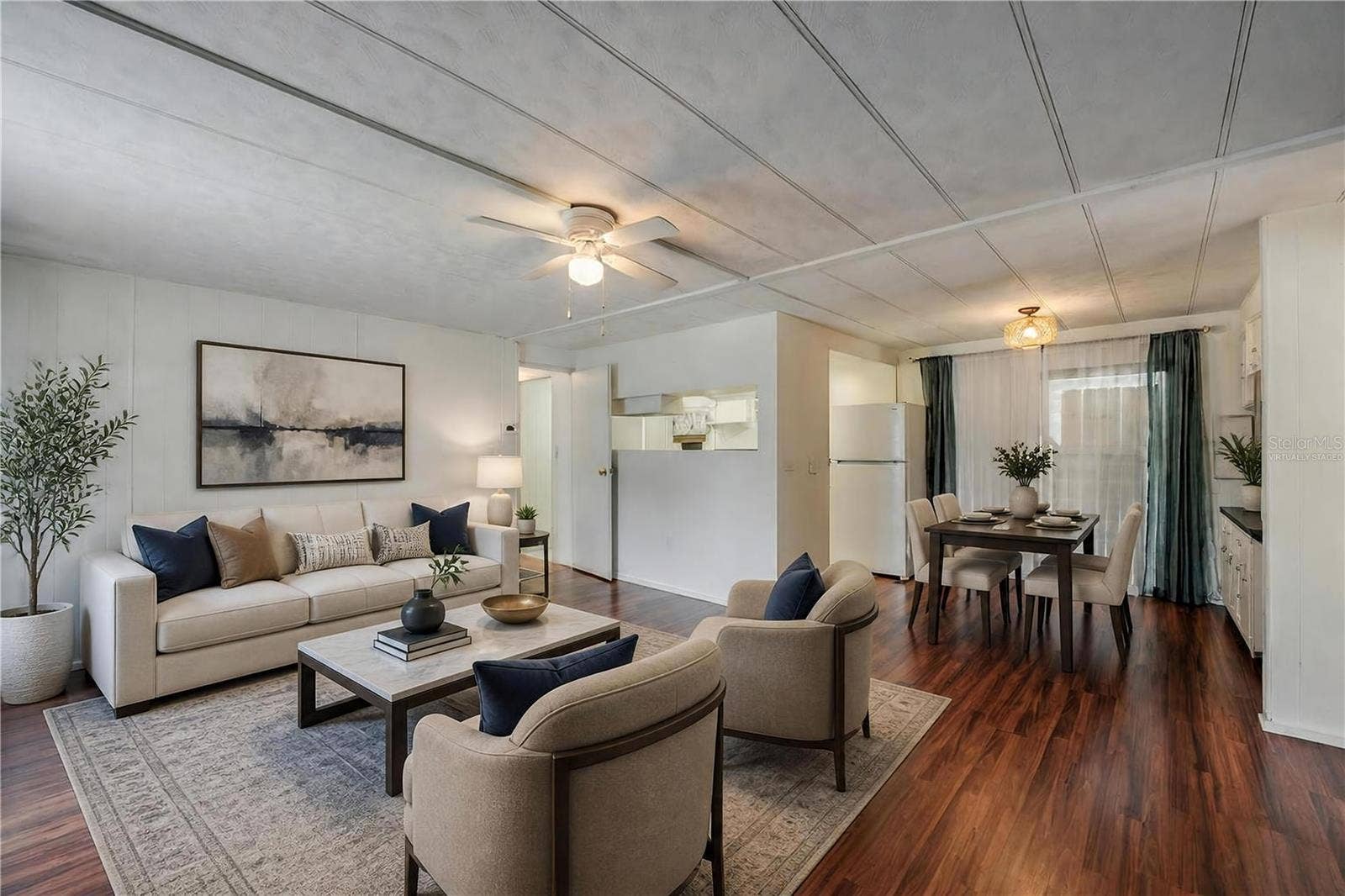 Virtually Staged - Wide-angle view highlights the open flow between the living, dining, and kitchen spaces, complemented by natural light from the large window.
