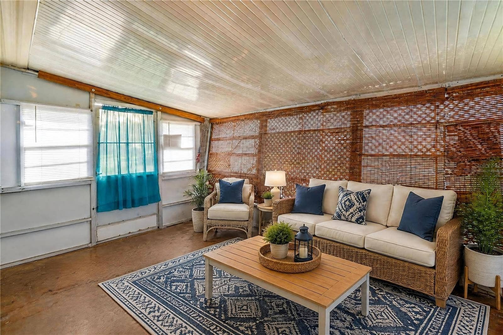 Virtually Staged - Expansive enclosed porch offers a flexible bonus space with numerous windows and woven shades for filtered natural light.