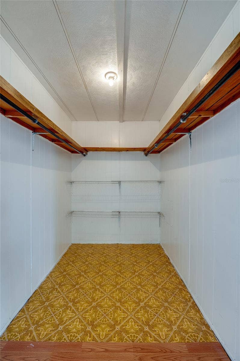 Generously sized walk-in closet provides hanging space and additional shelving for organized storage.